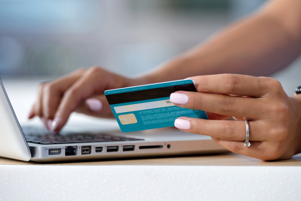 Woman holding a credit card and typing on a laptop
