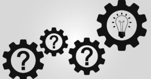 Four black gears with question marks in the middle. The largest gear on the right has a lightbulb instead of a question mark.
