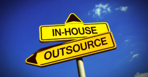 A Road sign with "In-House" on the top with an arrow pointing up and "Outsource" on the bottom with an arrow pointing left.