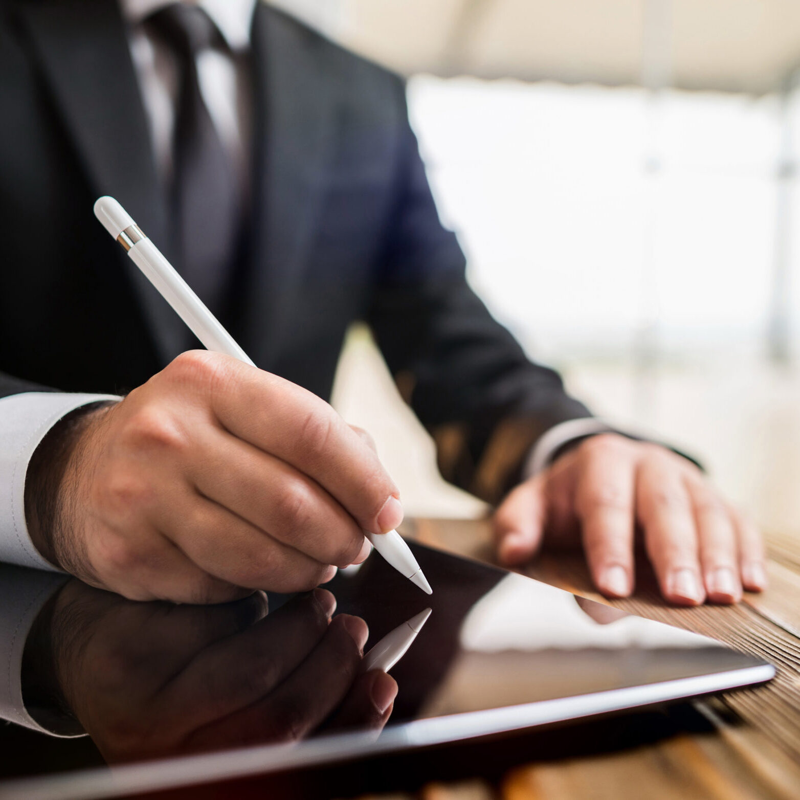 Man in a suit writing on a tablet with a stylus