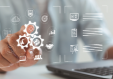 A digital overlay showing a person interacting with glowing gears and icons representing alarm company field service management software. Icons include a technician mobile app, automated scheduling, and paperless work order checklists over a laptop background.